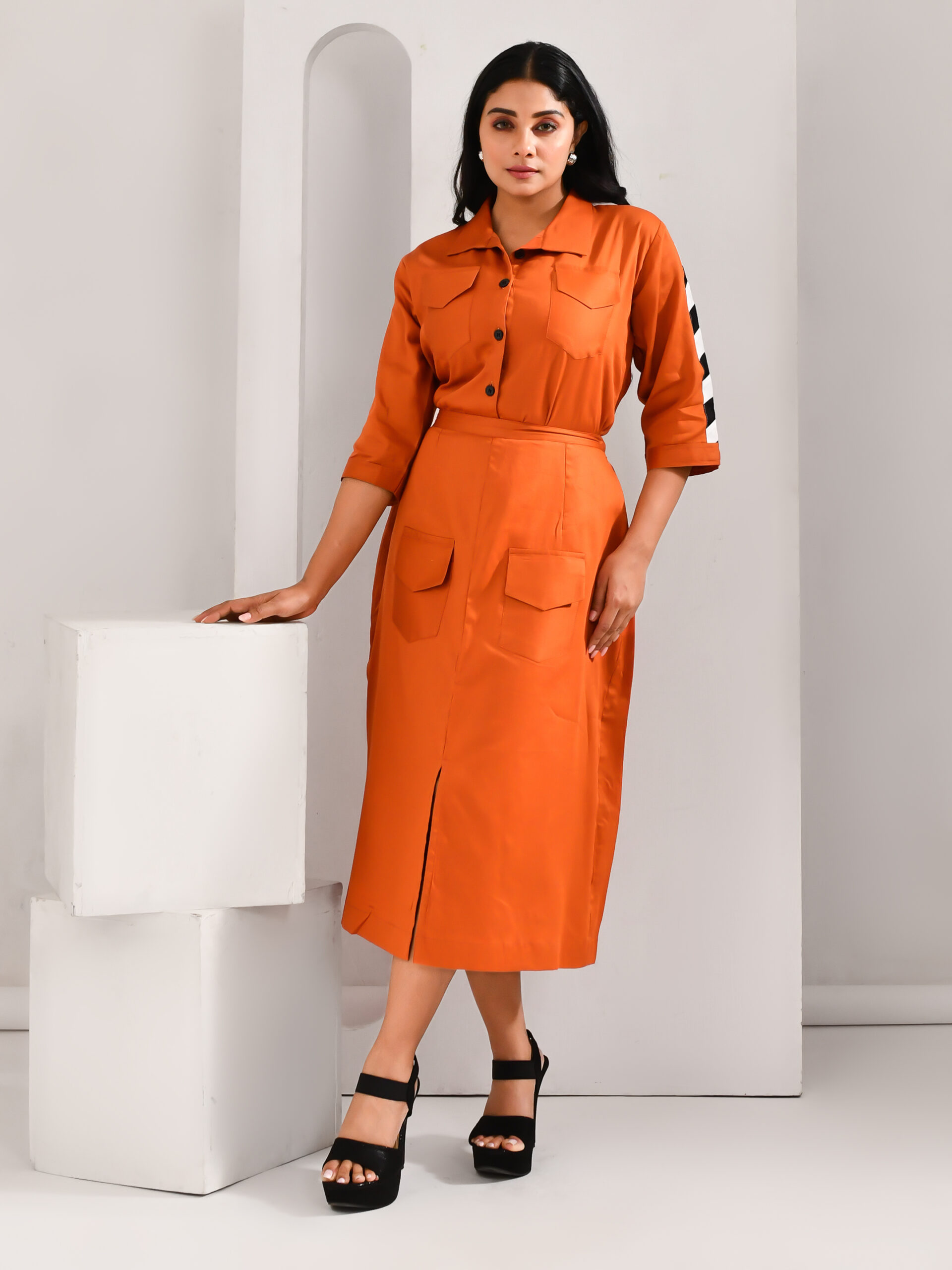 “Golden Muslin flame orange blended cotton co-ord set with crop shirt featuring shoulder detailing and matching skirt with pockets.”
