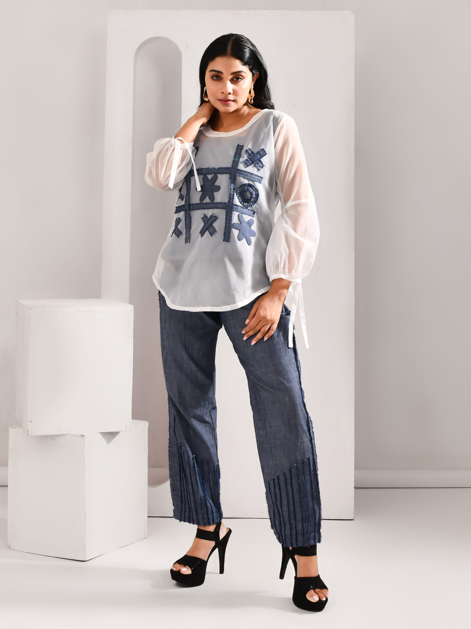 White patchworked top with denim game-pattern accents paired with frayed denim pants – Golden Muslin