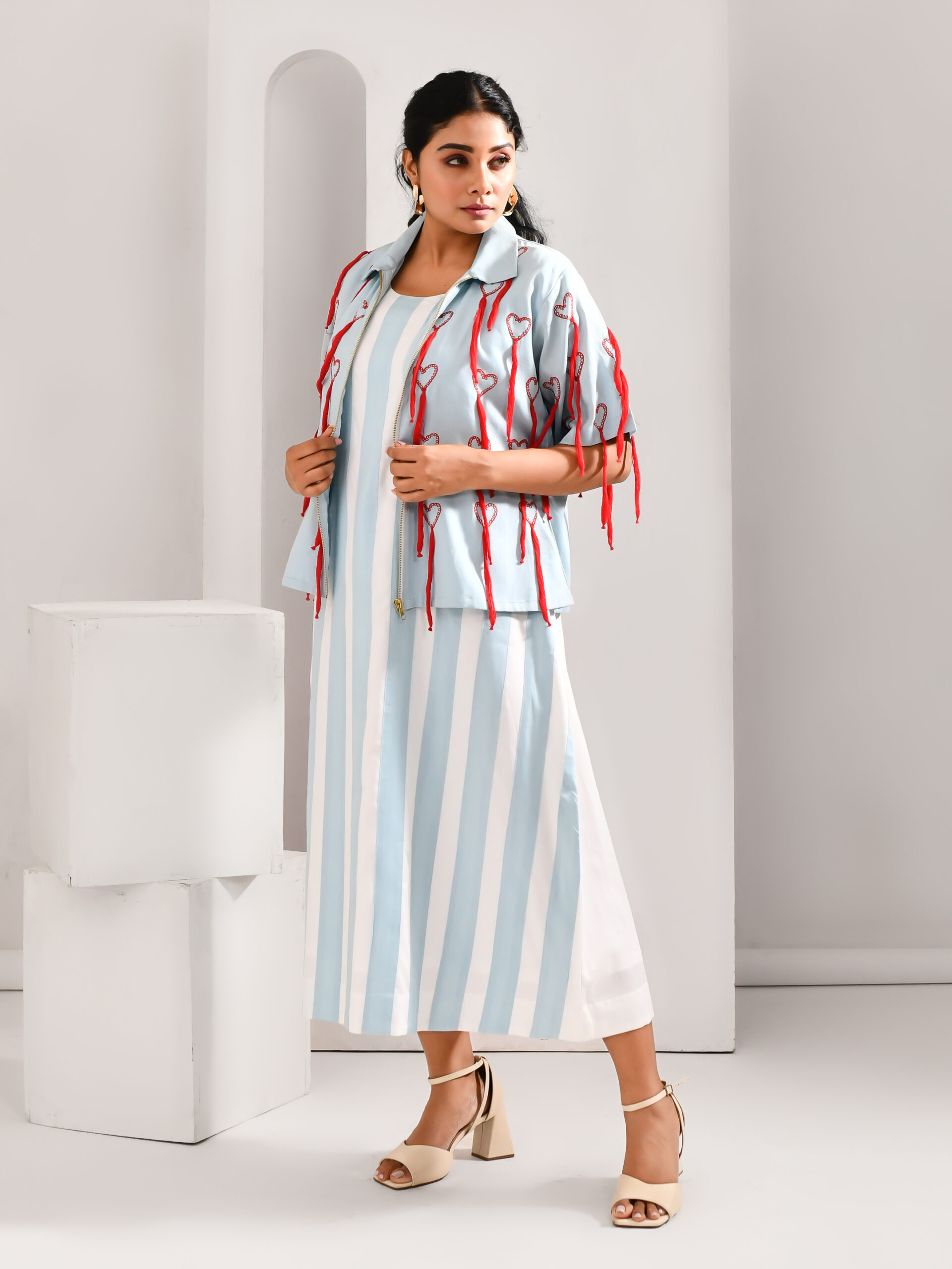 “Golden Muslin powder blue and white blended cotton dress with broad-stripe patchwork, paired with jacket featuring crimson quirky embroidery.”