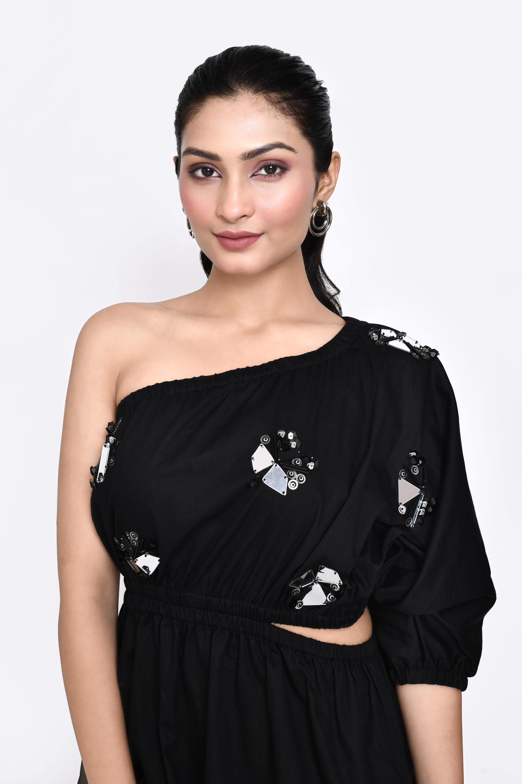 Golden Muslin Jaanvi Mohta black cotton satin one-shoulder dress with chunky embellishments and cut-out elasticated waist