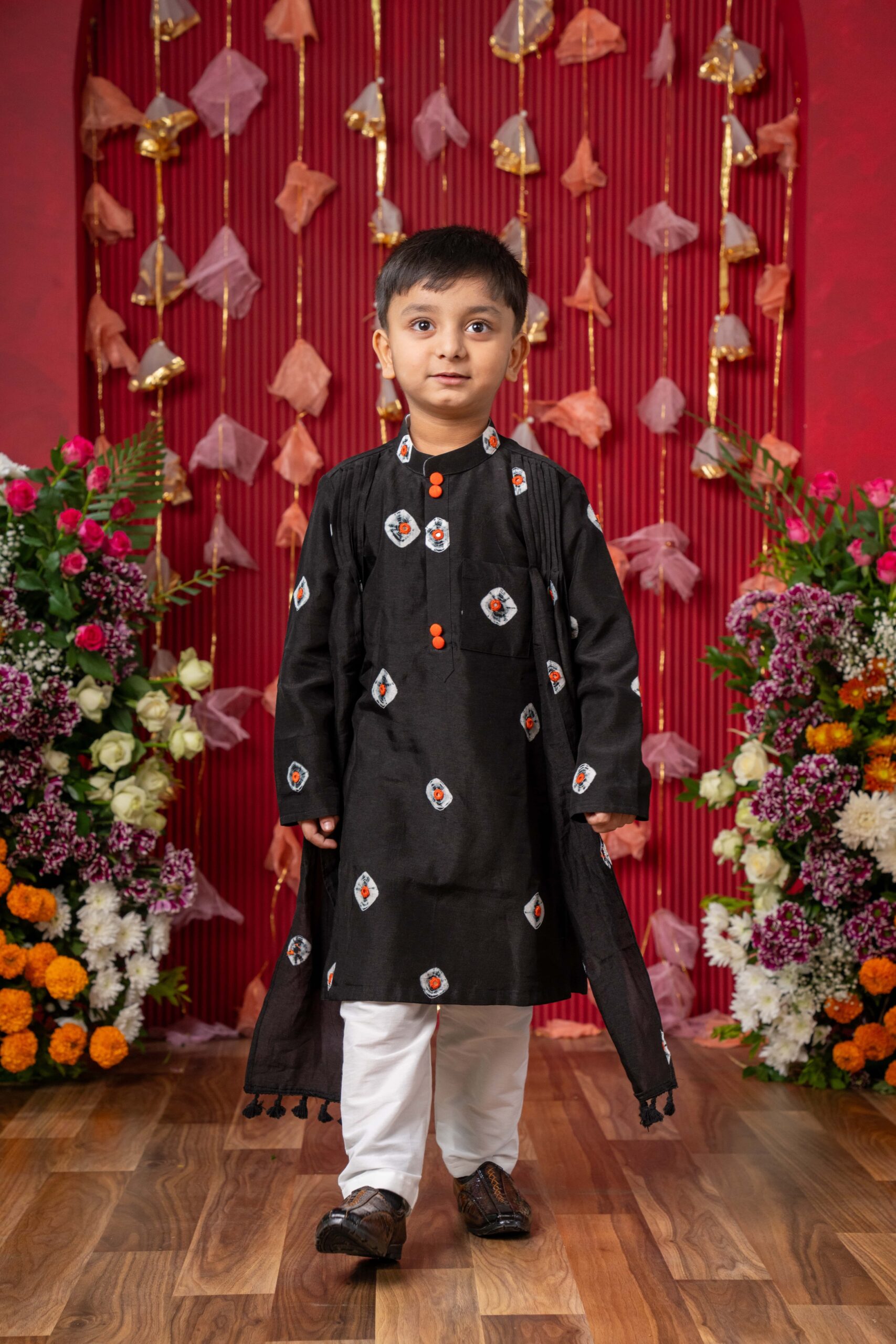 Black boys’ kurta with white and orange tie-dye, embroidered motifs, orange buttons, matching dupatta, and white pajama bottoms – Golden Muslin