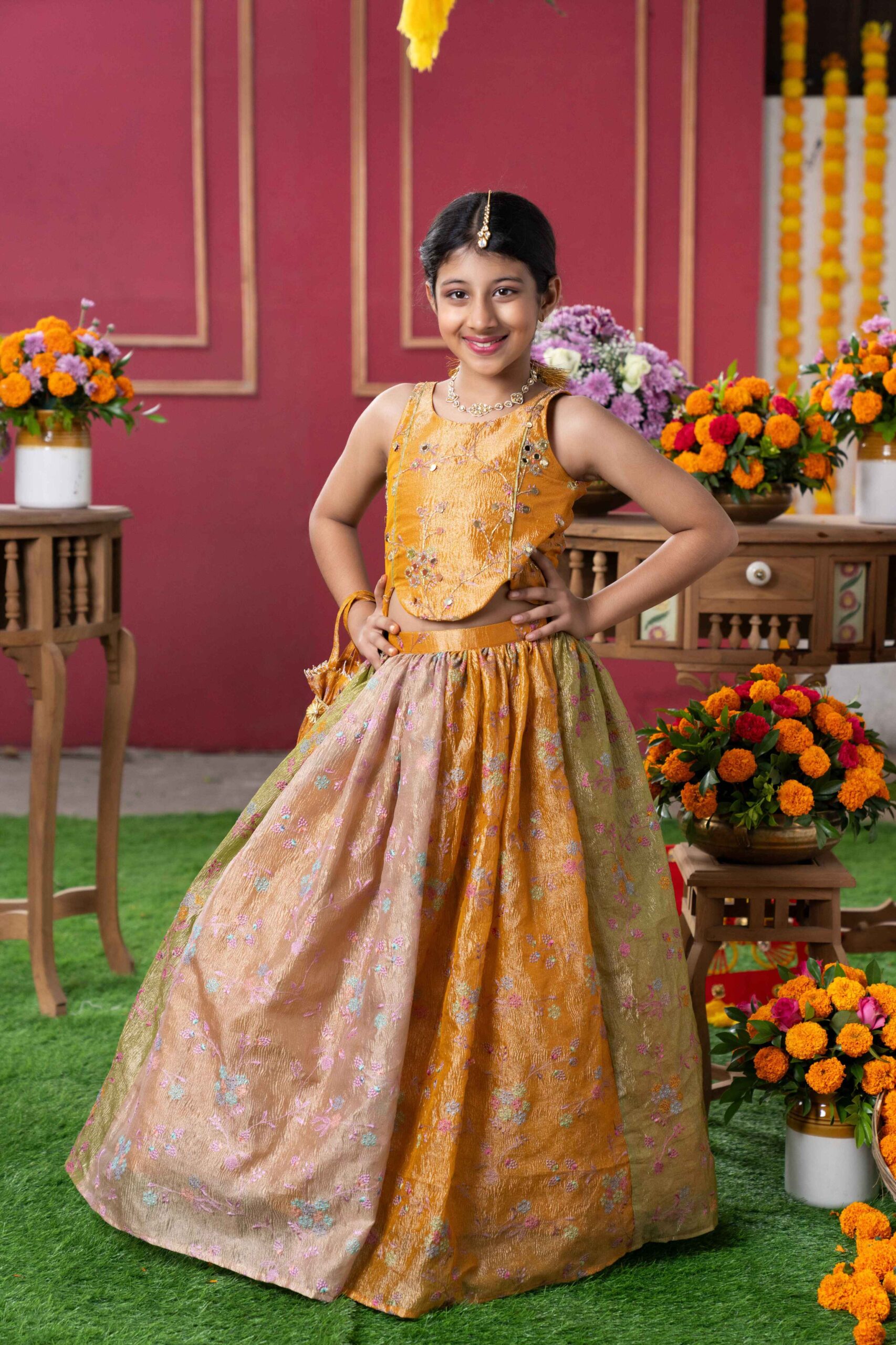 Mustard gold tissue silk girls’ lehenga set with embroidered asymmetrical blouse, beige-gold floral lehenga, and matching potli bag – Golden Muslin