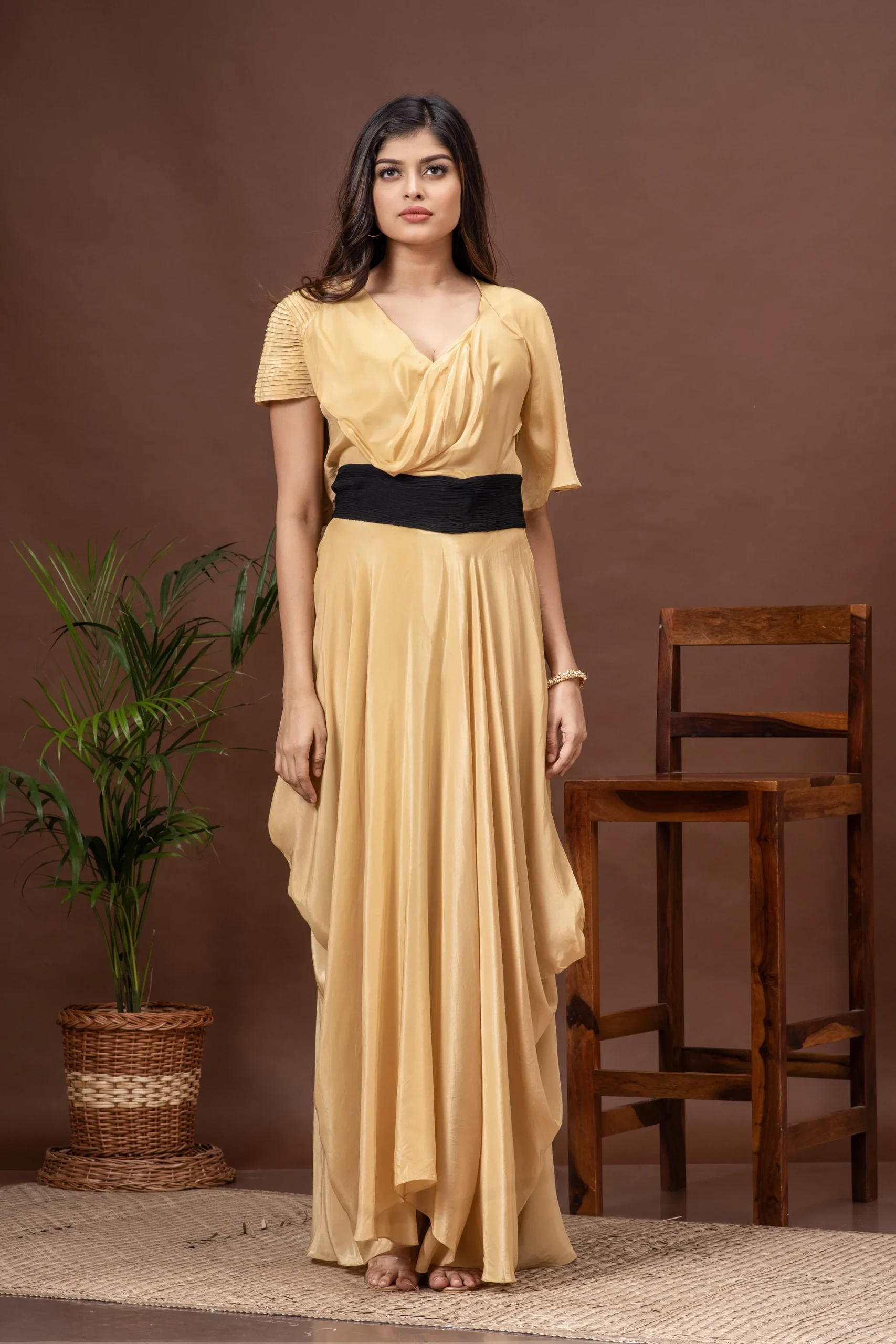 Beige V-neck crepe gown with cowls and asymmetric sleeves from the house of Golden Muslin by Kumar Rahul.