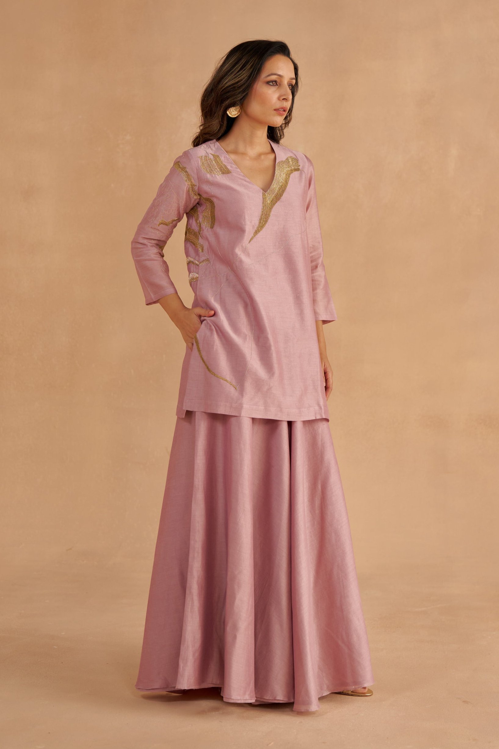 “Golden Muslin lilac Chanderi silk short kurta with Zardozi lotus motif and V-neckline, paired with lilac Chanderi Sharara pants with waist belt, pockets, and modern slit.”