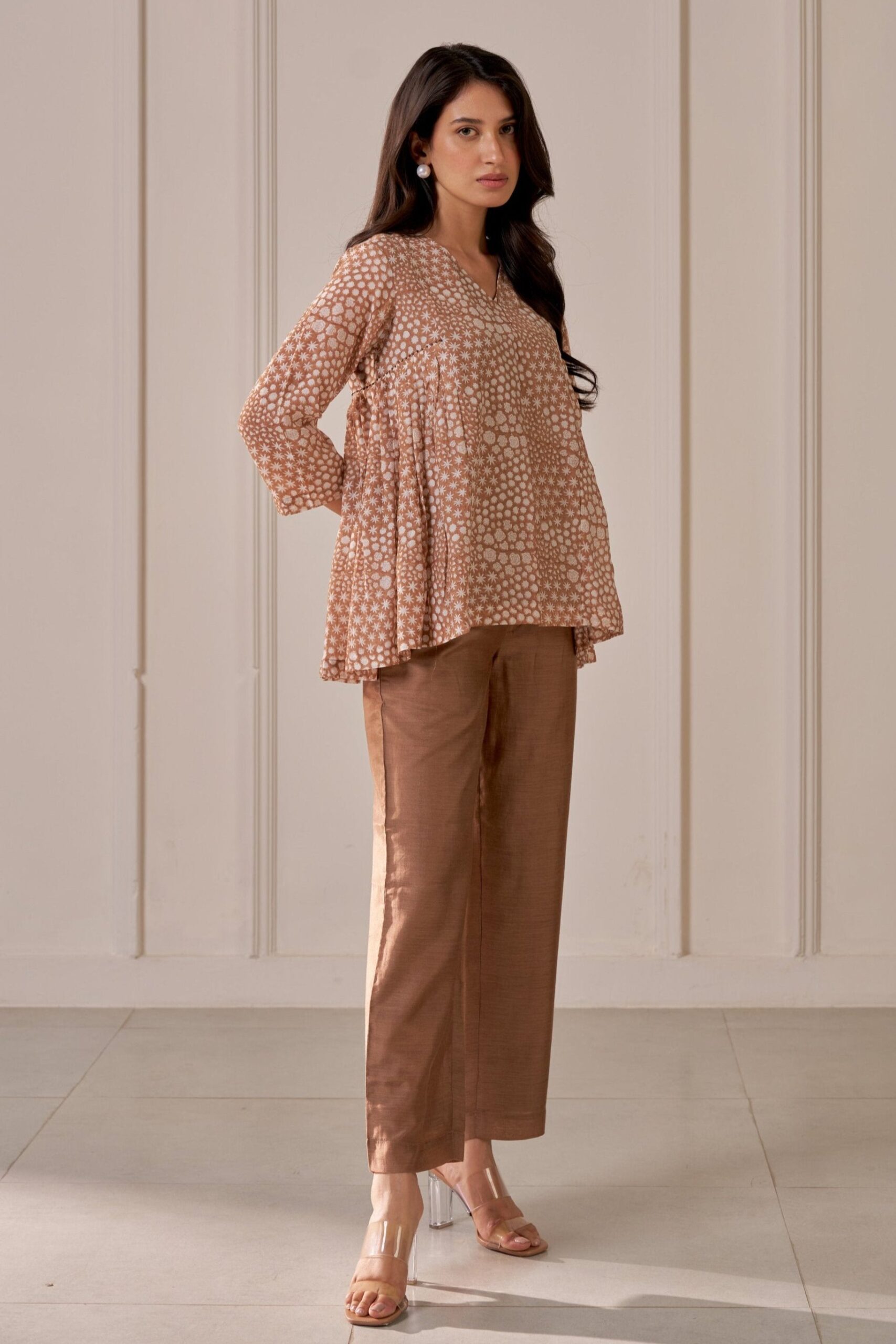 “Golden Muslin brown muslin silk pleated V-neck top with floral block print, paired with matching straight-leg tailored trousers.”
