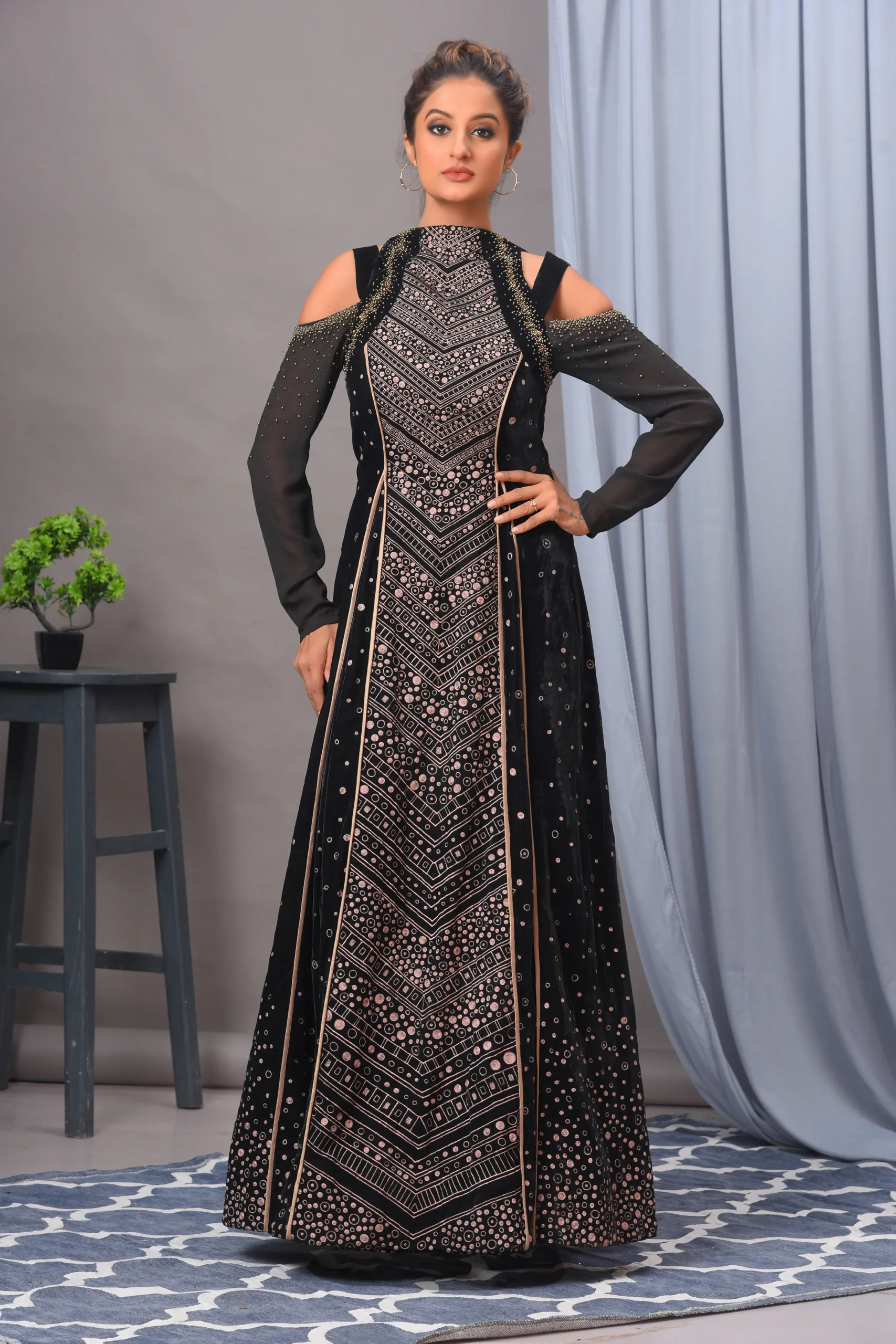 A luxurious black velvet full cold-shoulder gown from Golden Muslin By Vivek Kumar featuring unique embellishments and rich intricate embroidery.