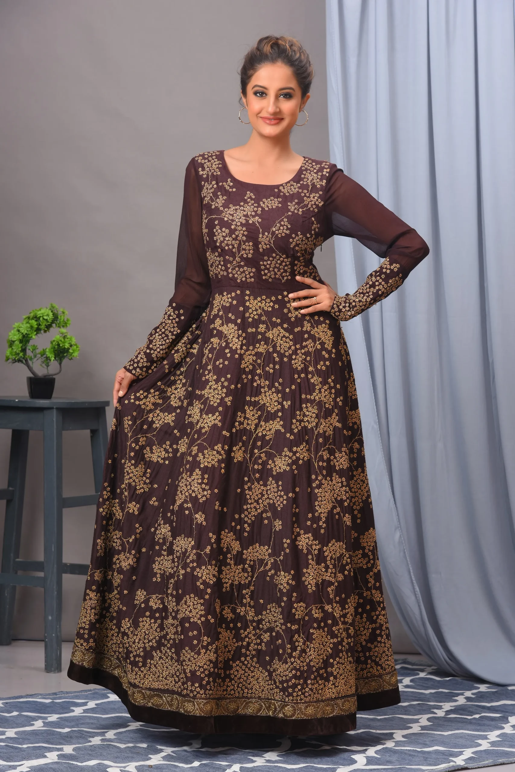 A coffee-colored Matka silk gown by Vivek Kumar from Golden Muslin, featuring intricate antique gold embroidery and a contemporary silhouette.