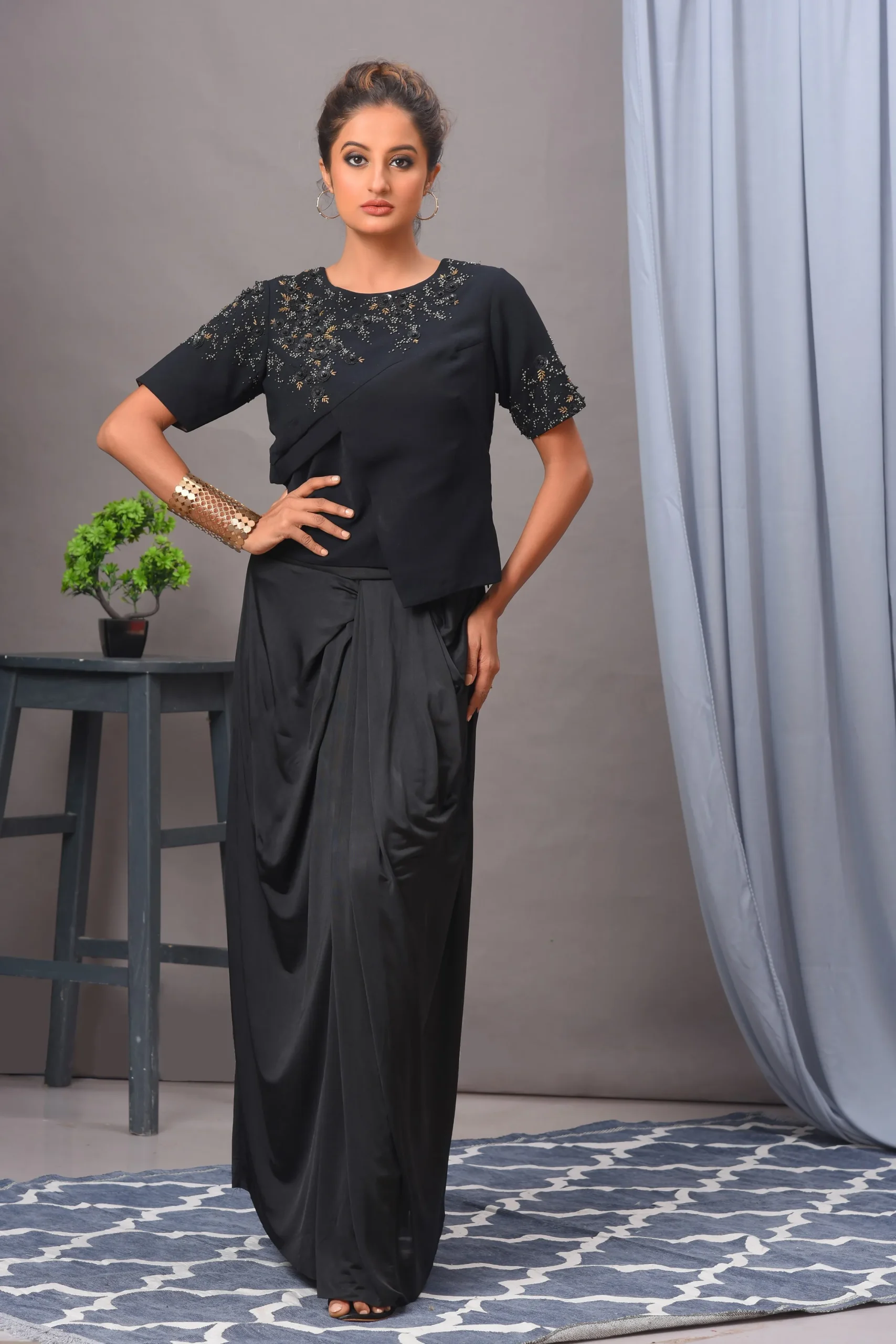 A black Indo-Western set from Golden Muslin By Vivek Kumar featuring a crisscross double georgette top and a dramatic draped spandex skirt.