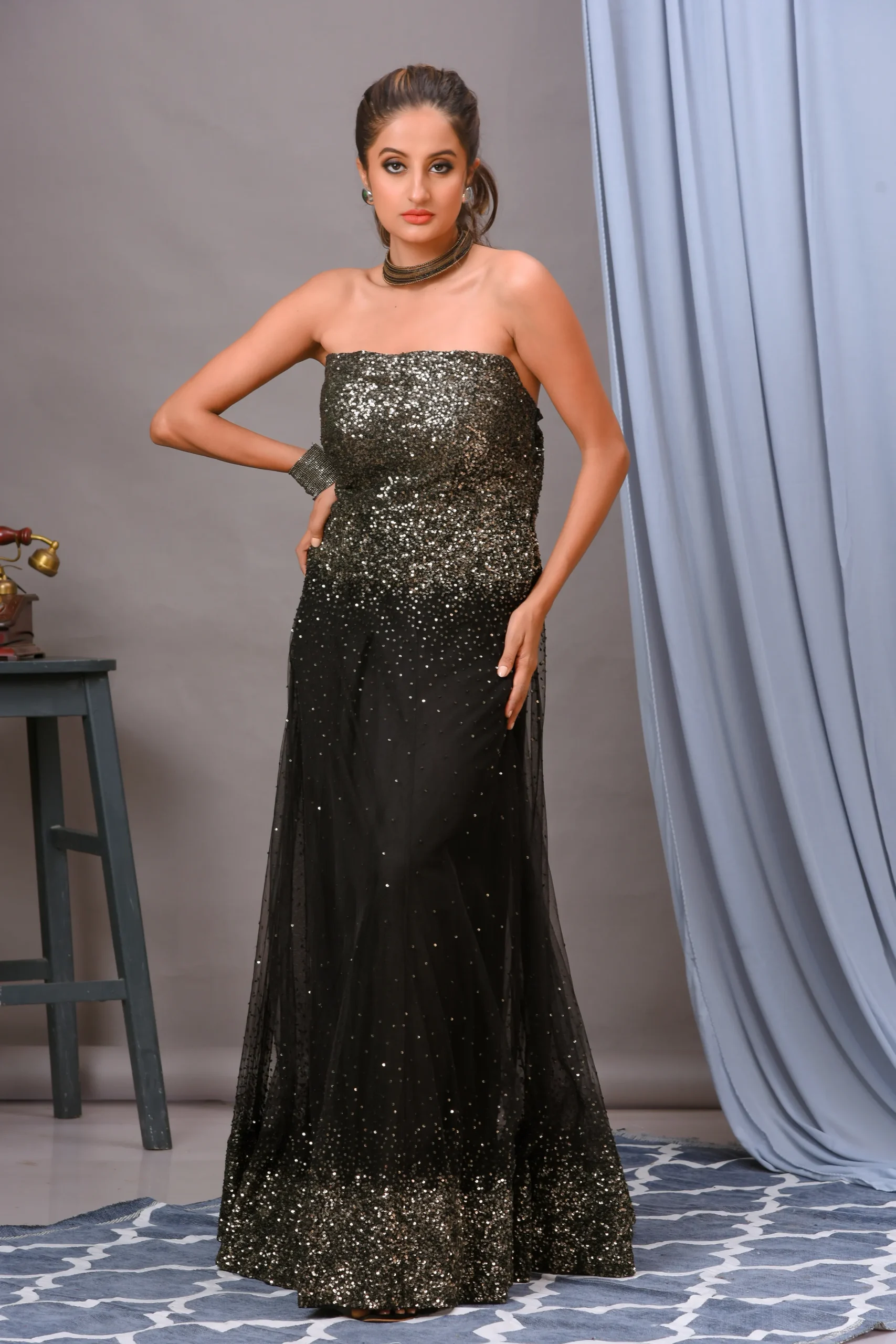 A stunning black net off-shoulder gown from Golden Muslin By Vivek Kumar, featuring intricate embroidery and shimmering embellishments for a contemporary look.