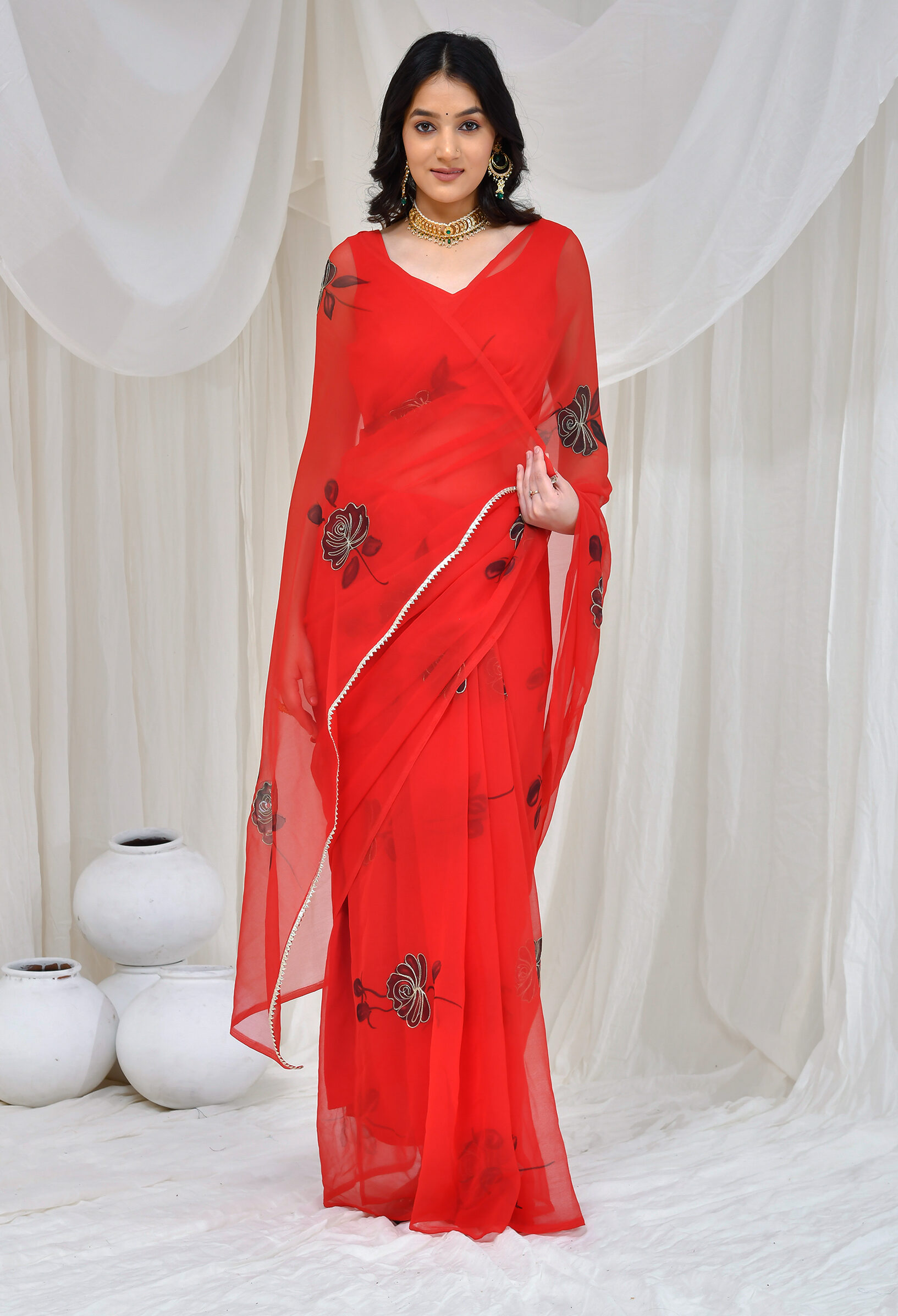 Red hand-painted georgette saree with intricate aari embroidery, fluid drape, and refined festive detailing in Golden Muslin by Priyanka Rathore