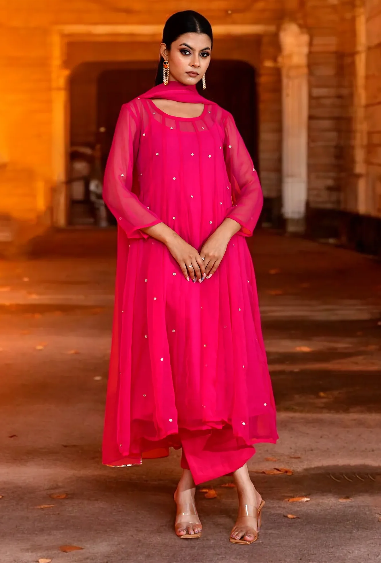 A bold fuchsia georgette Anarkali featuring intricate aari embroidery and a fluid silhouette from Golden Muslin by Priyanka Rathore for a refined festive look.