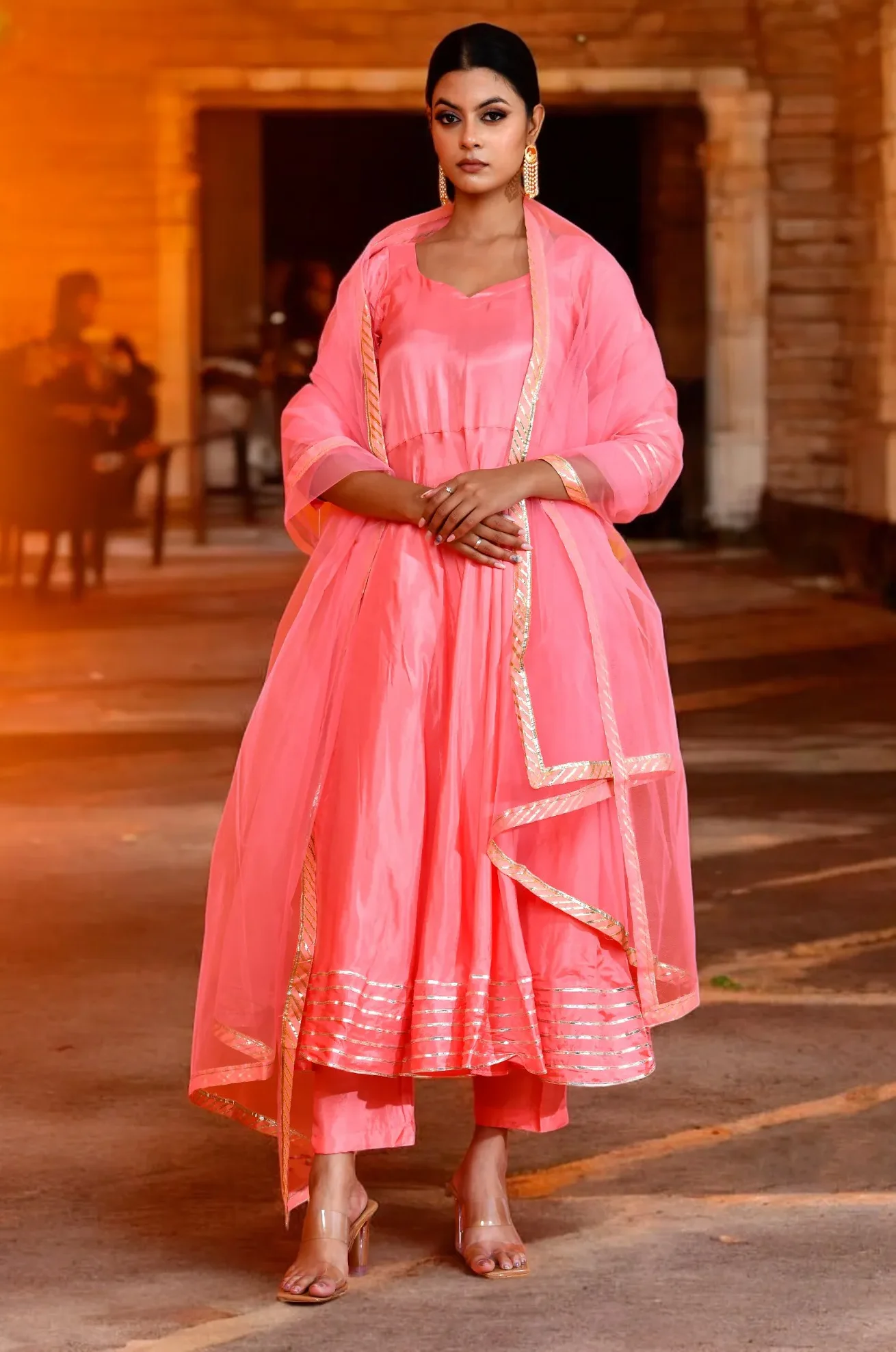 An elegant pink Uppada silk Anarkali featuring soft gota work detailing and a luminous finish from Golden Muslin by Priyanka Rathore, ideal for festive celebrations.