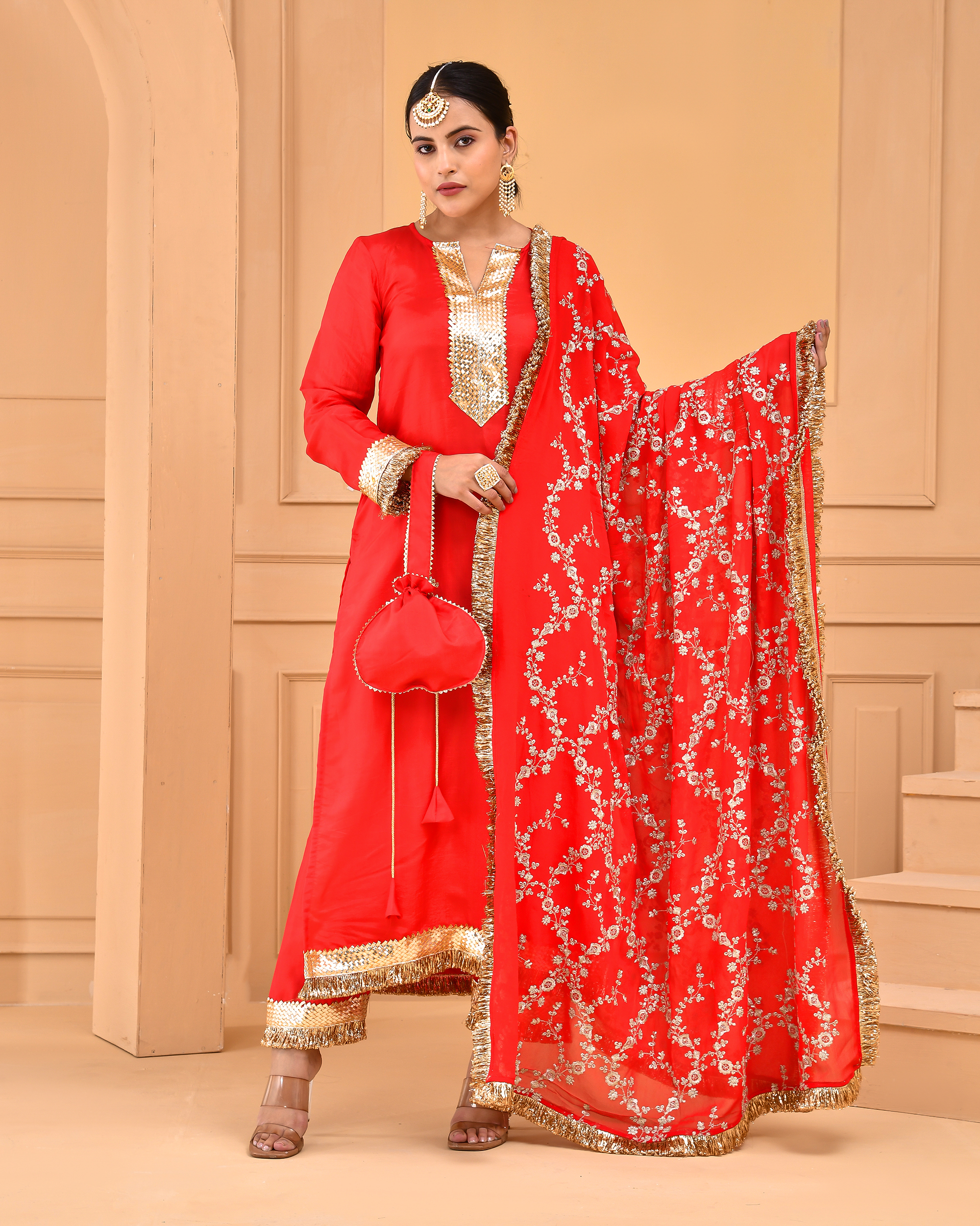 Red Uppada silk straight kurta set with gota detailing on yoke, sleeves, hem, matching pants with gota work, and heavily embroidered dupatta with gota borders and potli in Golden Muslin by Priyanka Rathore