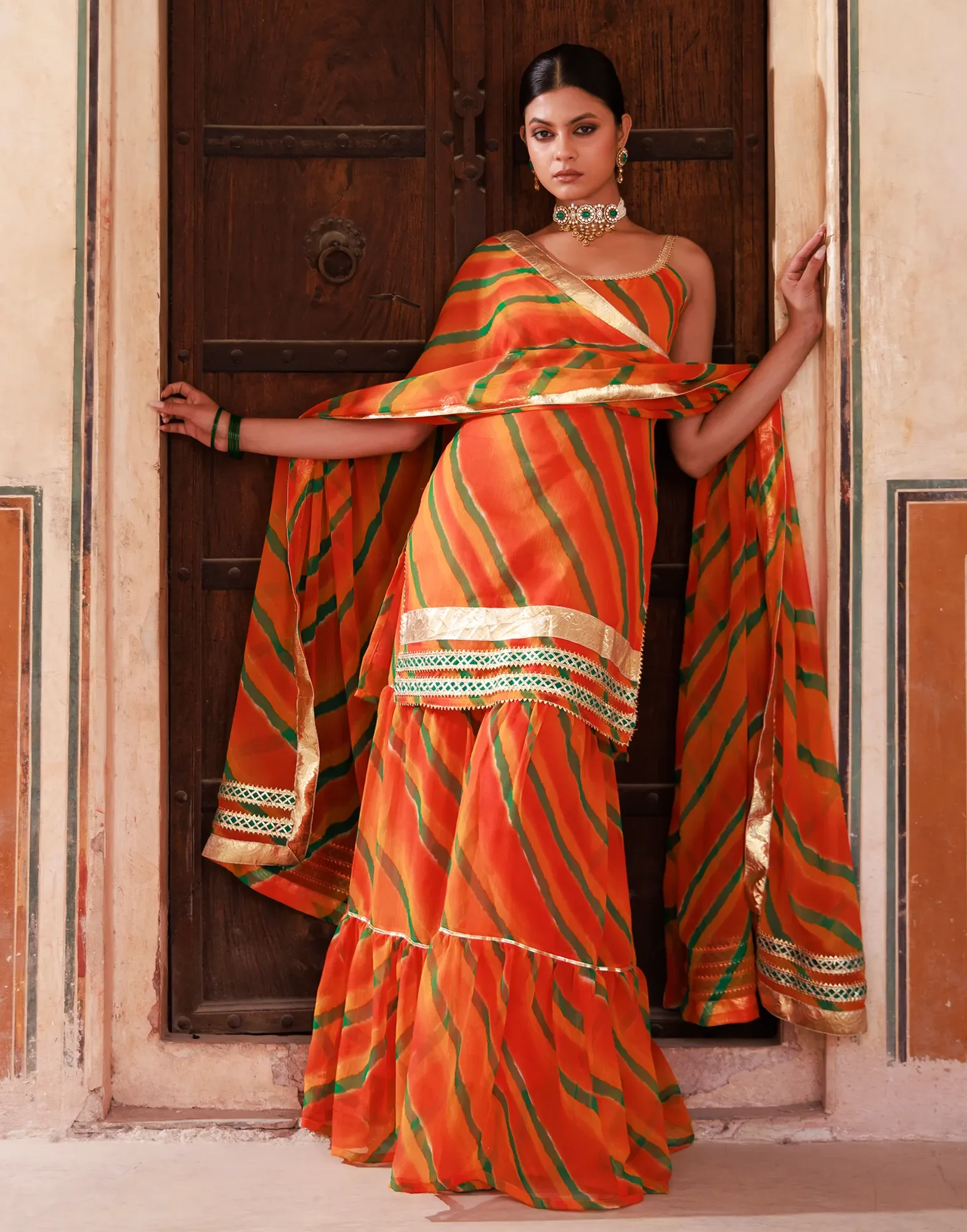 Orange chiffon sharara set with strappy kurta, gota accents and sequin lace borders from Golden Muslin by Priyanka Rathore