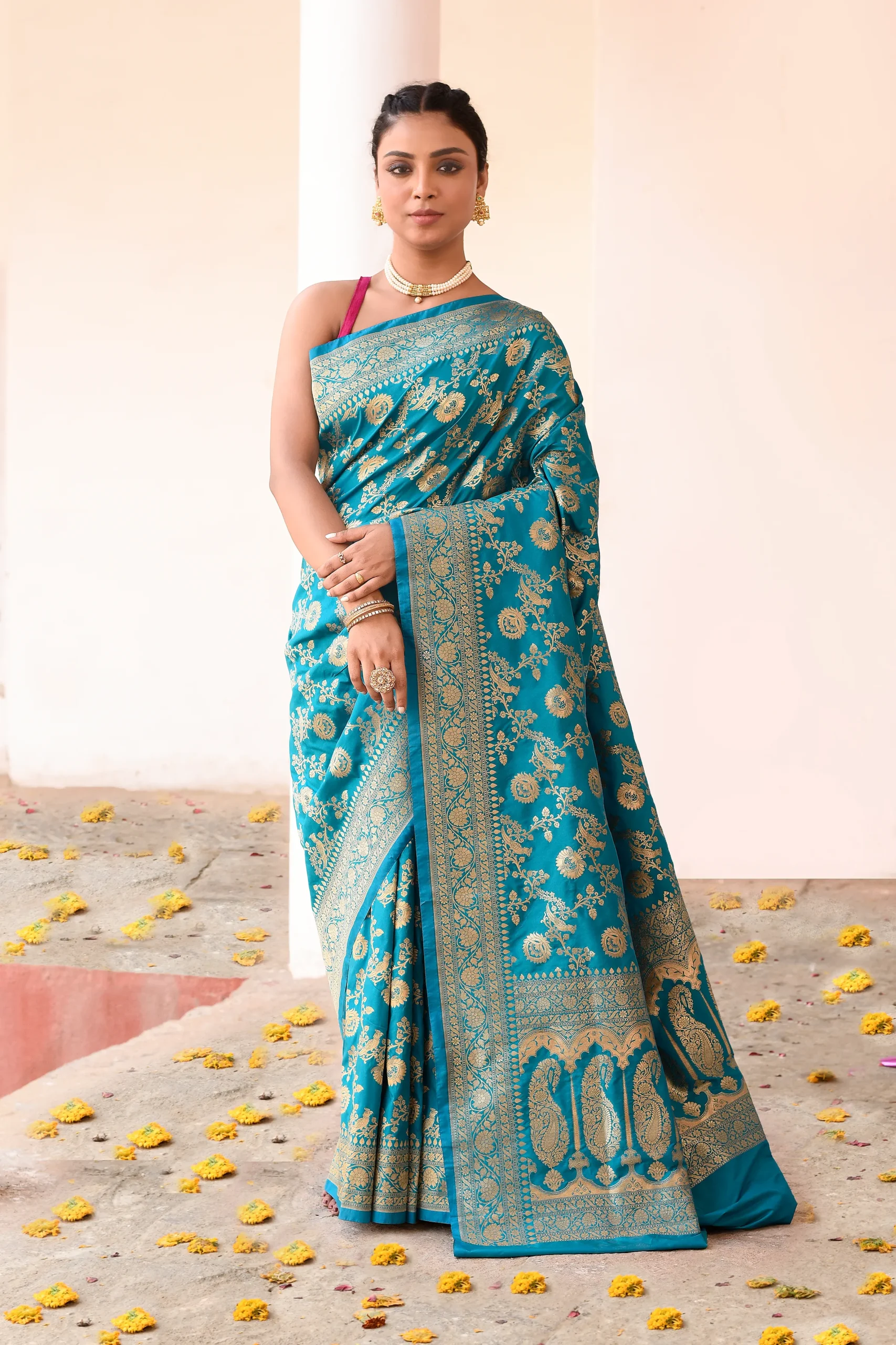 Teal blue soft silk Banarasi saree with floral motifs and antique gold zari border from Golden Muslin By Naaritva Banaras