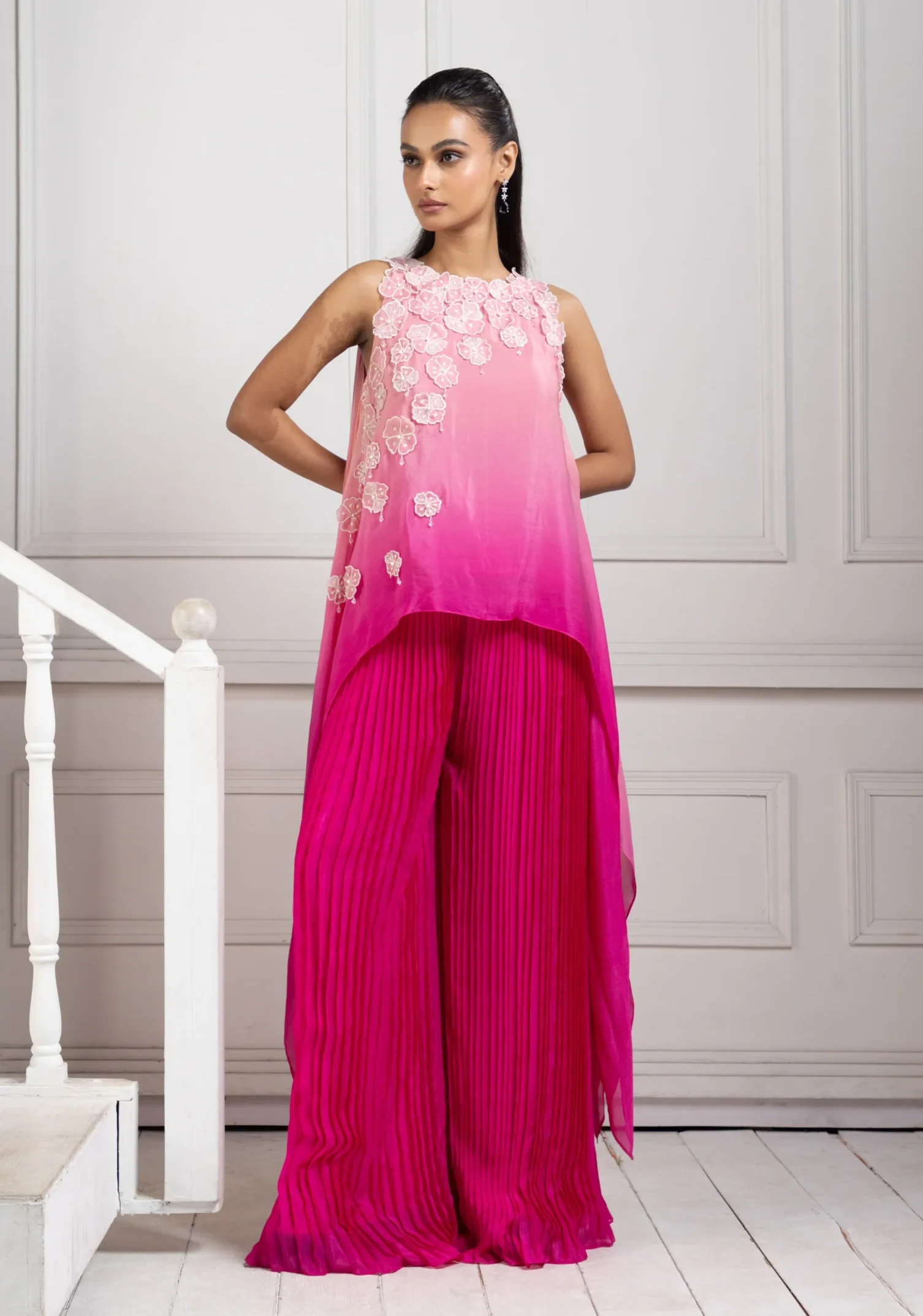 Model wearing rani pink golden muslin asymmetric floral applique set with pleated cascade pants