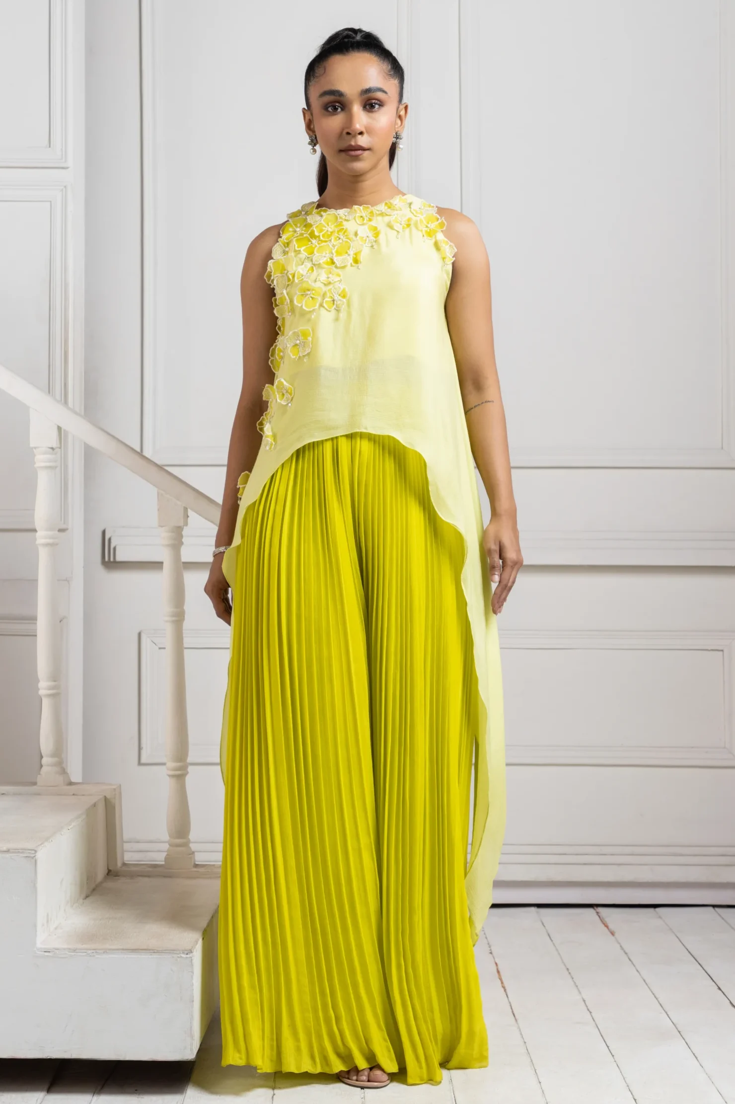 Model wearing yellow golden muslin asymmetric chiffon cape with lemon green pleated cascade pants