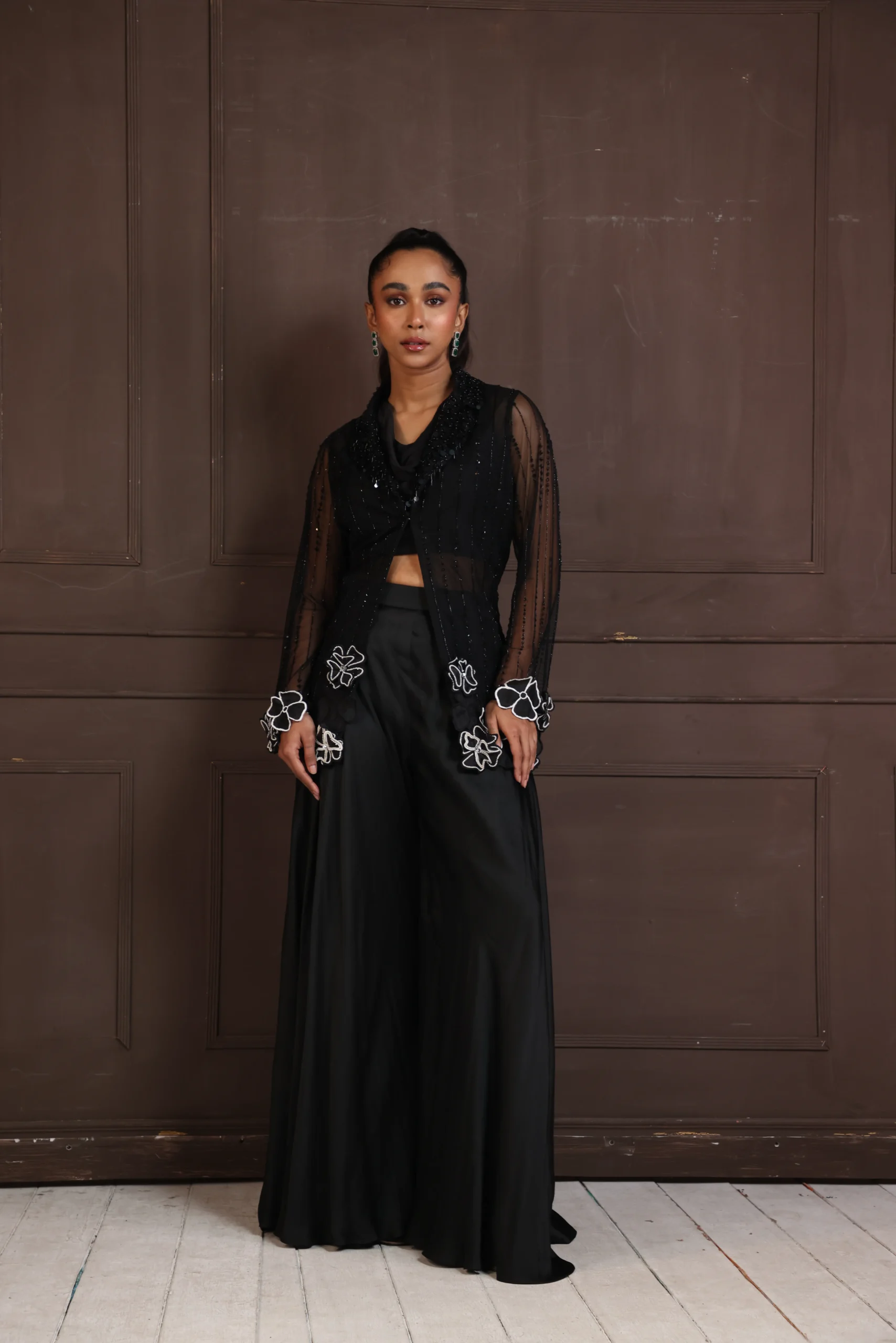 Model wearing black golden muslin bold evening co ord set with sheer panel bodice and wide leg palazzo trousers