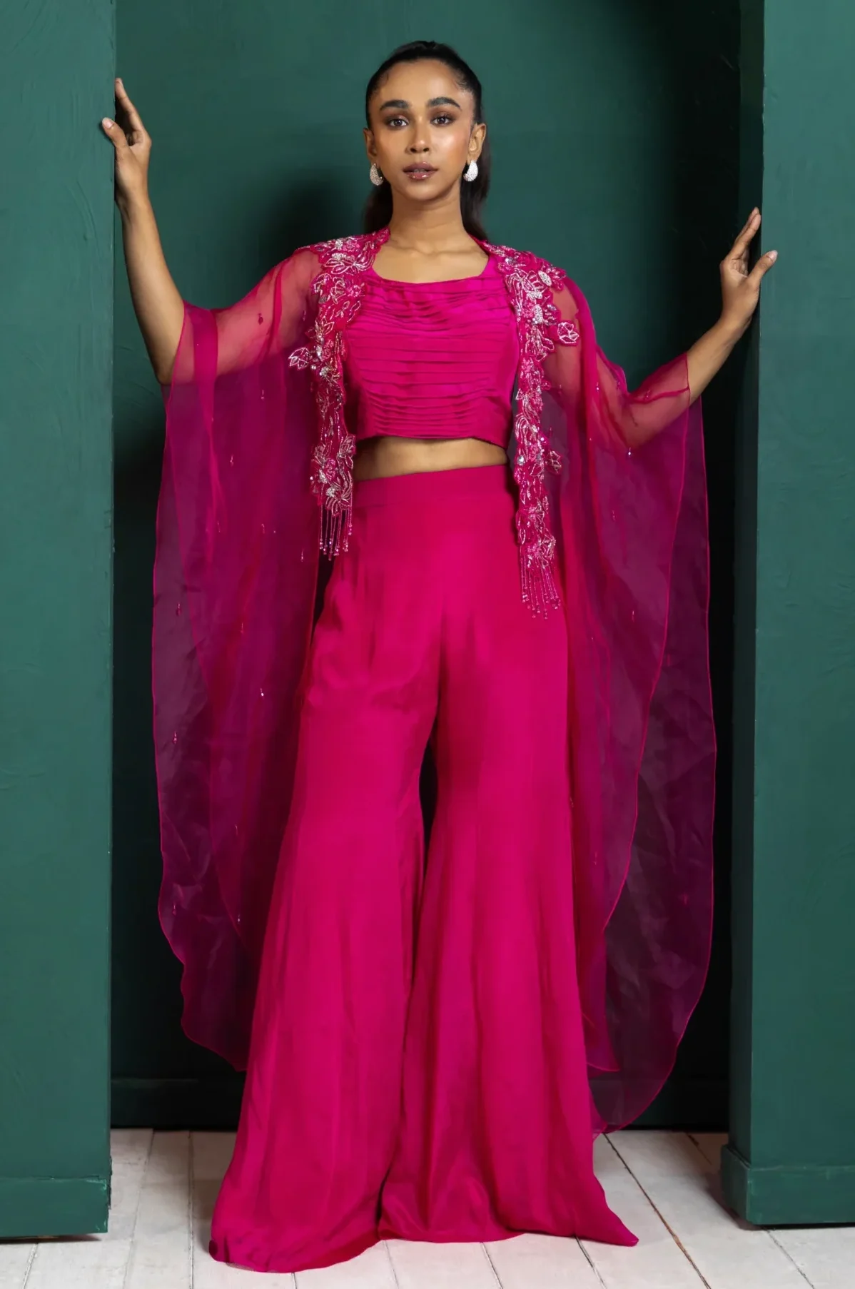 Model wearing berry golden muslin embellished co ord set with sheer beaded cape and wide leg pants