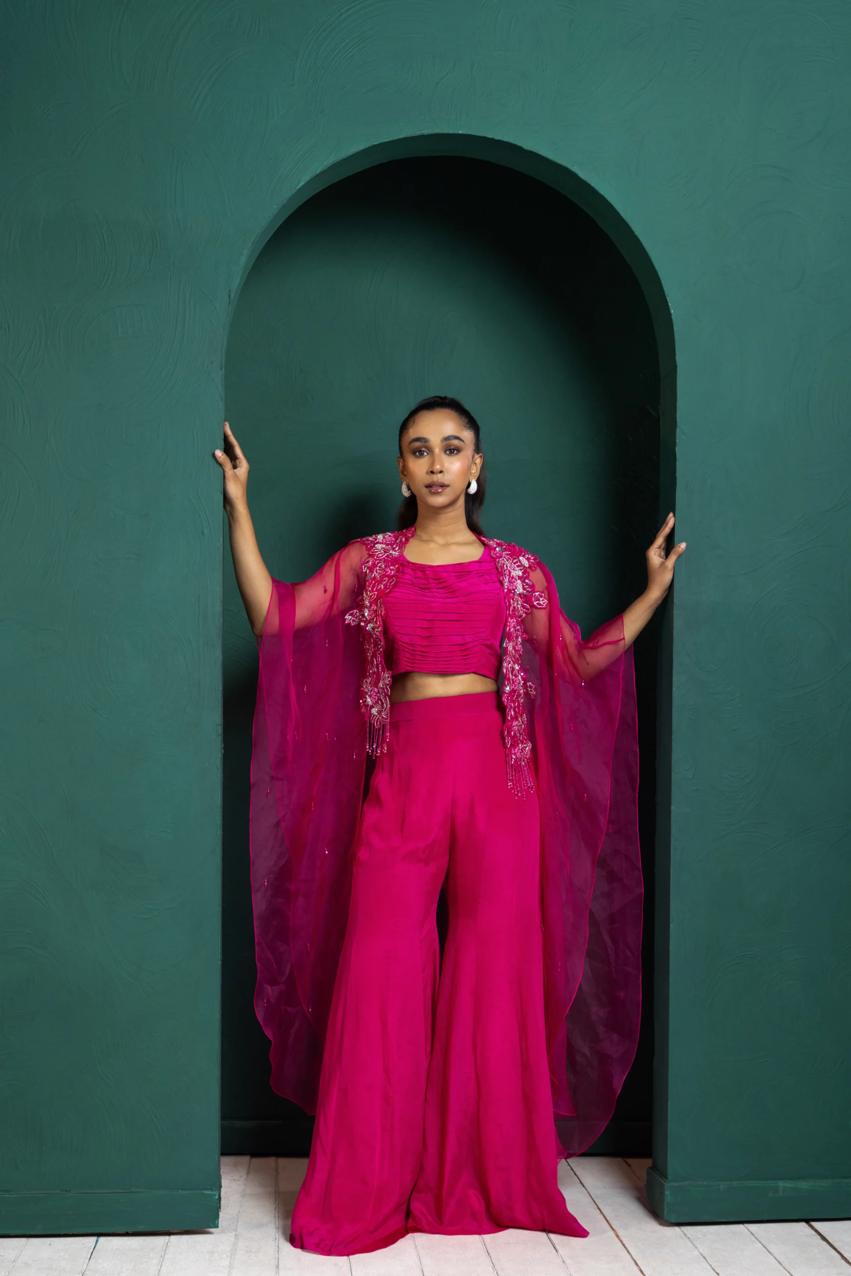 Model wearing berry golden muslin embellished co ord set with sheer beaded cape and wide leg pants